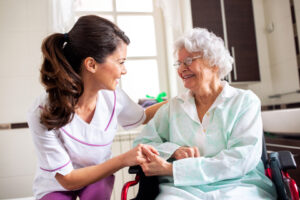 photo of elderly woman in wheelchair being helped by client care worker